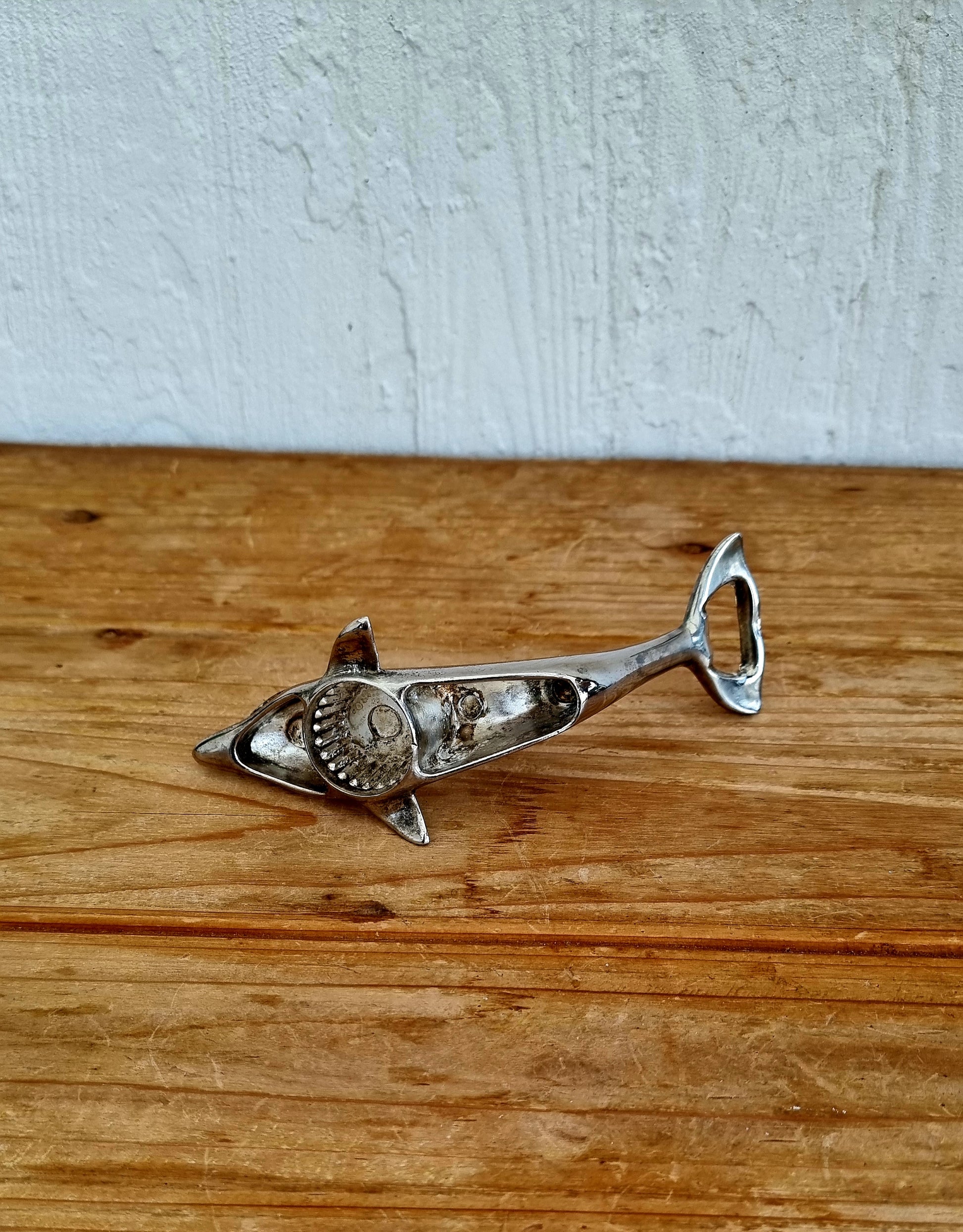 Décapsuleur vintage en métal chromé en forme de dauphin, objet rétro des années 70, à la fois décoratif et fonctionnel. 