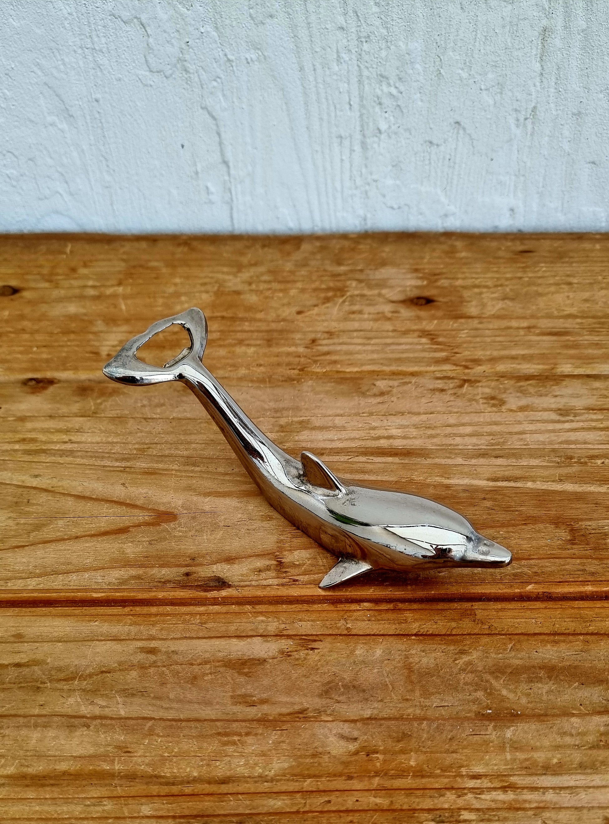 Décapsuleur vintage en métal chromé en forme de dauphin, objet rétro des années 70, à la fois décoratif et fonctionnel. 