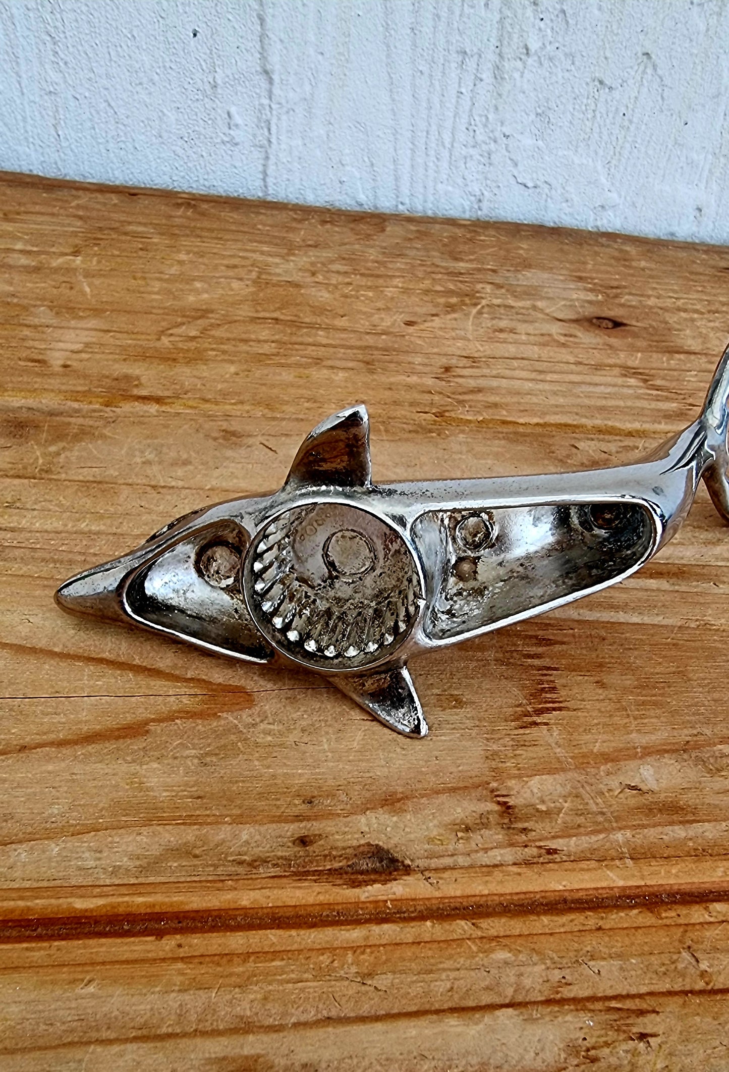 Décapsuleur vintage en métal chromé en forme de dauphin, objet rétro des années 70, à la fois décoratif et fonctionnel.