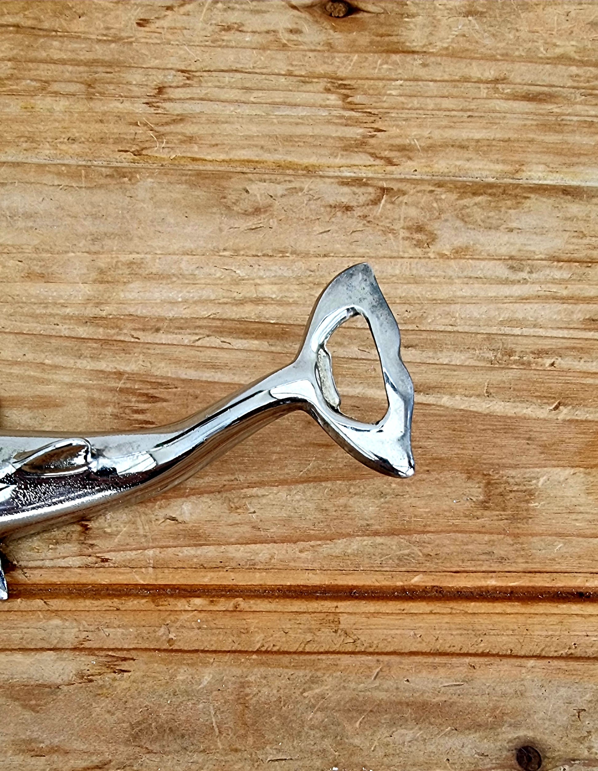 Décapsuleur vintage en métal chromé en forme de dauphin, objet rétro des années 70, à la fois décoratif et fonctionnel. 