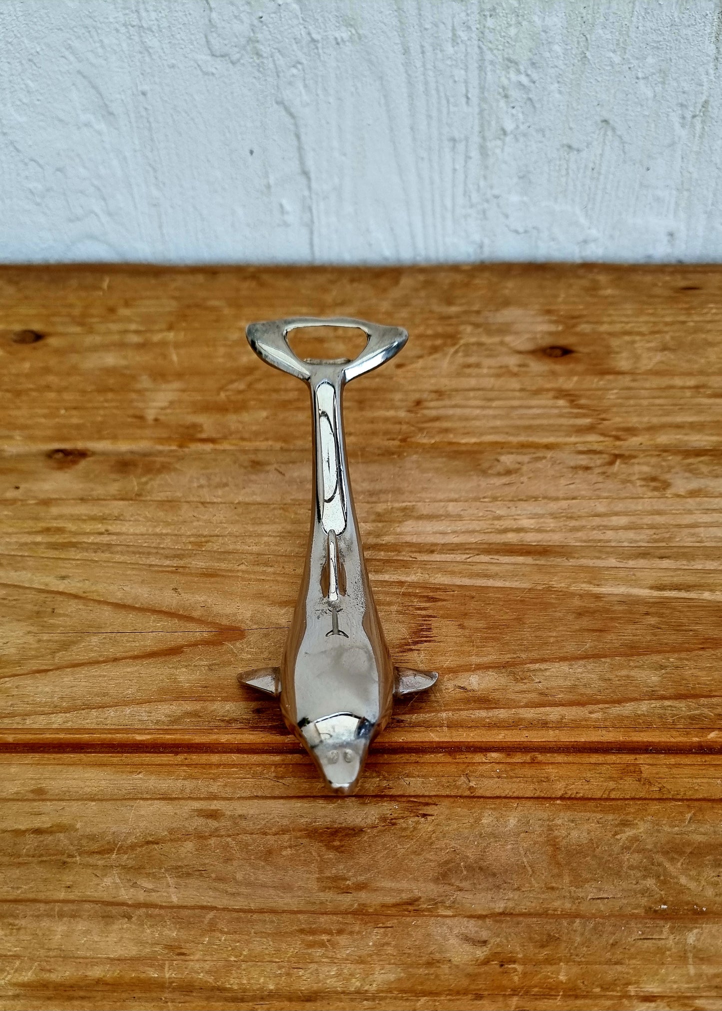 Décapsuleur vintage en métal chromé en forme de dauphin, objet rétro des années 70, à la fois décoratif et fonctionnel. 